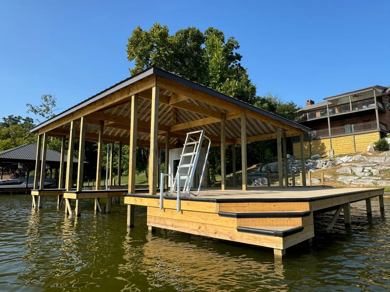 Newly built covered wooden dock with a ladder and steps into the lake