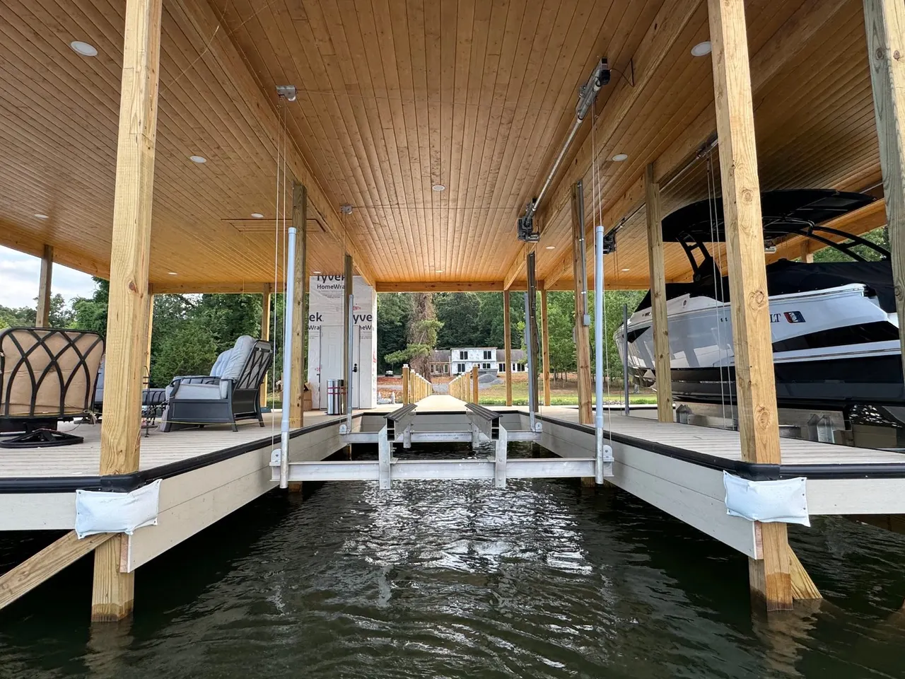 Inside a covered boathouse with a wood ceiling and a boat on its lift