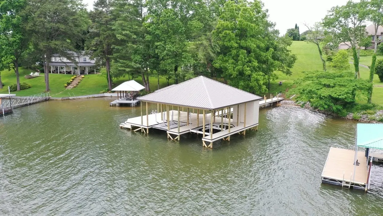 Aerial view of a covered boat dock with a hip roof on a calm cove